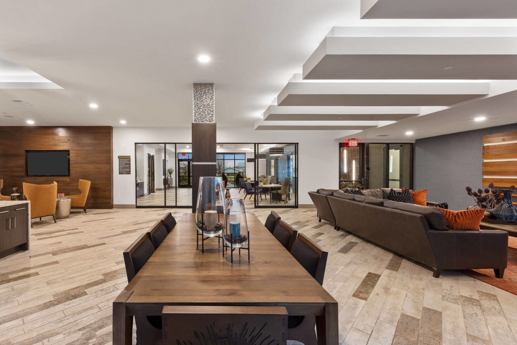 Clubhouse area with long table, lounge seating, and accent wall with flat screen tv