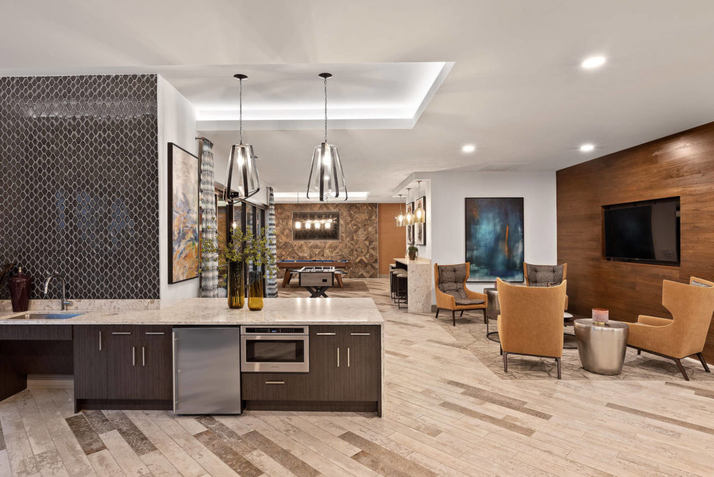 Clubhouse area with lounge area, flat screen TV on wooden accent wall, bar area with microwave, and pool table
