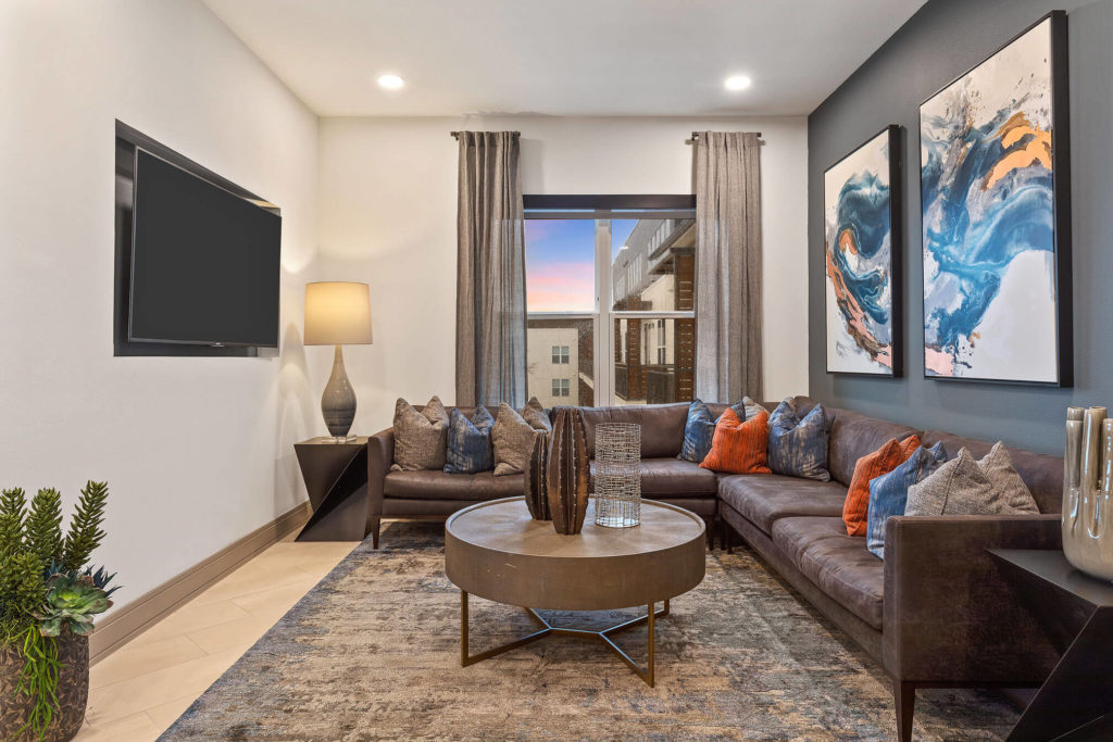 Clubhouse area with large sectional seating, blue accent wall and wall mounted flat screen TV