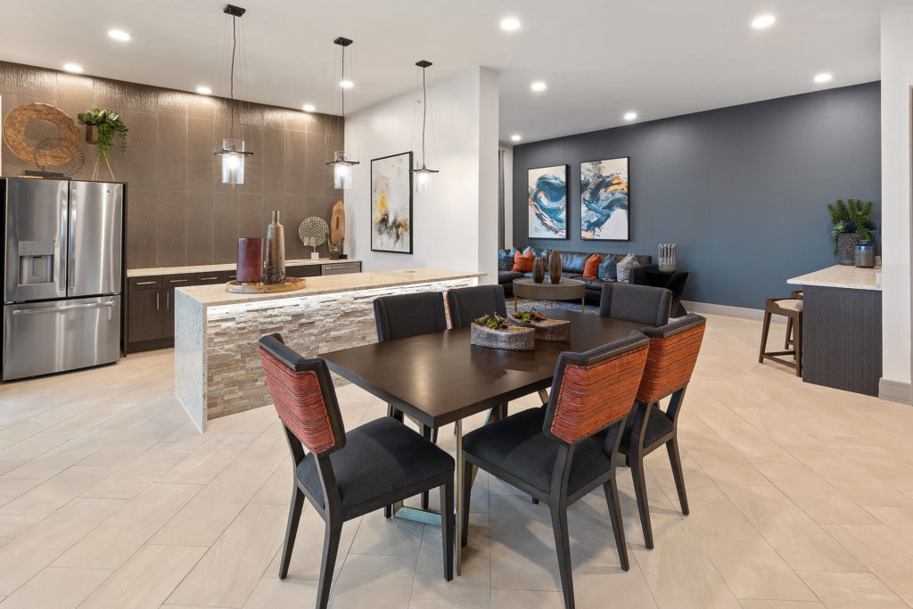 Clubhouse kitchen area with long table, pendant lighting, community fridge and bar area