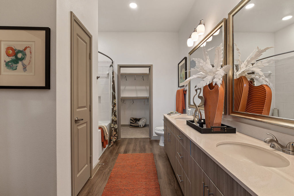 Bathroom with dual sinks, two large mirrors, linen closet, walk-in closet, and large tub/shower