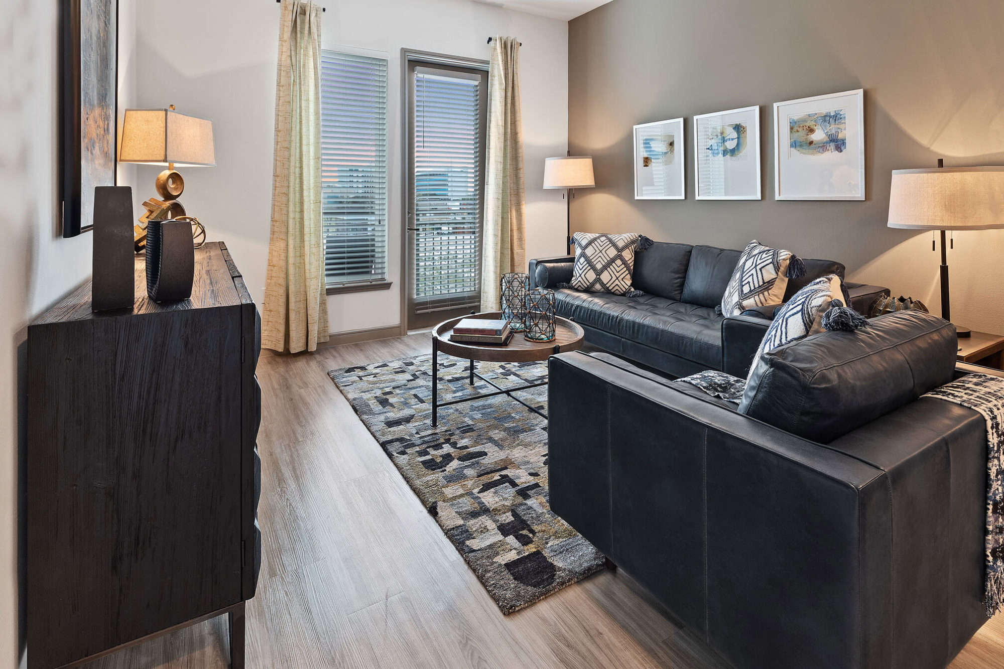 Living room with door to patio/balcony, modern furniture, tan accent wall, and wood like flooring