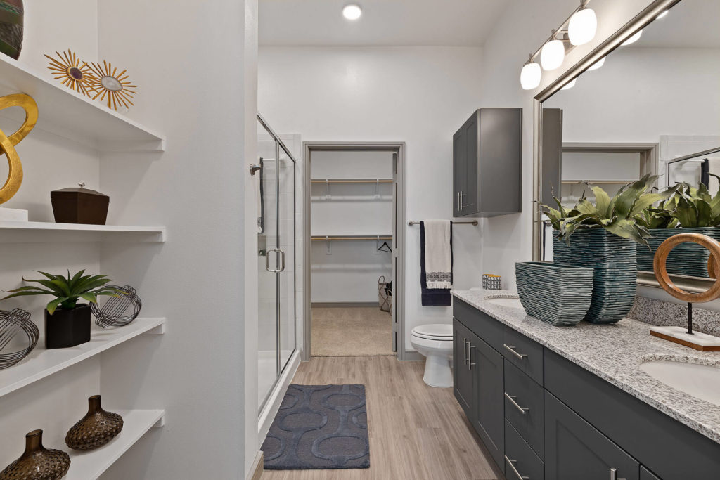 Bathroom with walk-in shower, walk-in closet, designer lighting, dual sinks and built in shelving