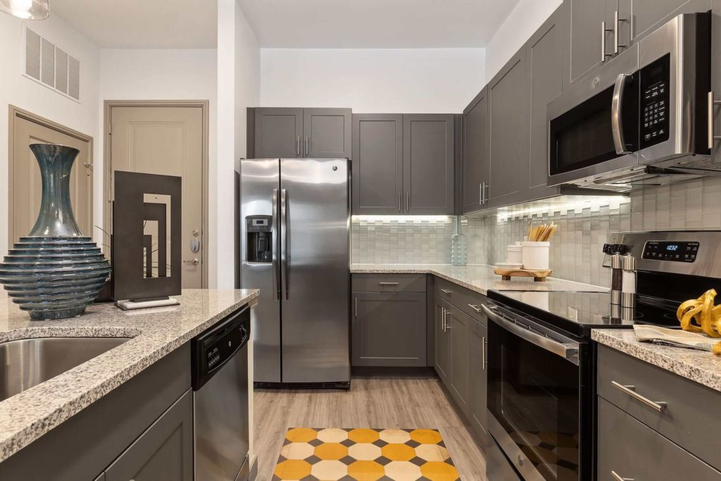 Kitchen with stainless steel appliances, wood-like floors, island, and designer cabinetry