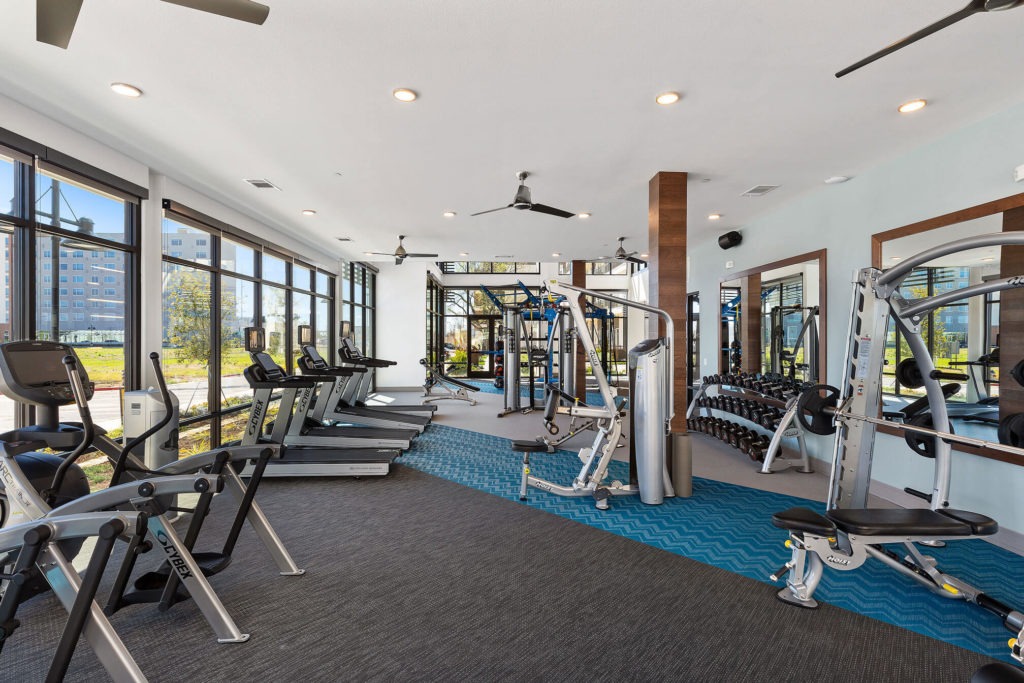 Fitness center with cardio and weight machines, free weights, floor to ceiling windows and ceiling fans