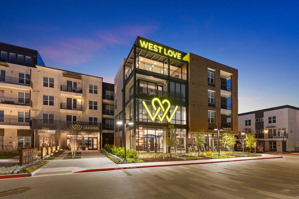 West Love leasing and community building with decorative landscaping and neon signage